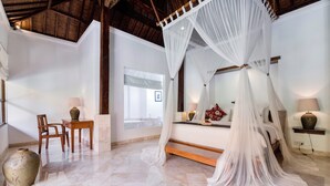 A bedroom with a four-poster bed, a sitting area with a table and chairs, and a large vase on the floor. - Alam Bidadari Seminyak Villas (Seminyak)