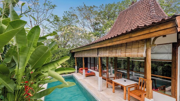 A poolside area with a covered seating area, wooden furniture, and a view of the pool. - Alam Bidadari Seminyak Villas (Seminyak)