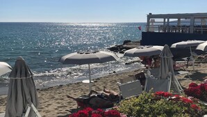 Une plage avec des parasols, des chaises longues et un poste de surveillance pour les sauveteurs.