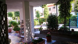 Un espace extérieur abrité, agrémenté de plantes en pot et doté d’un sol carrelé.
