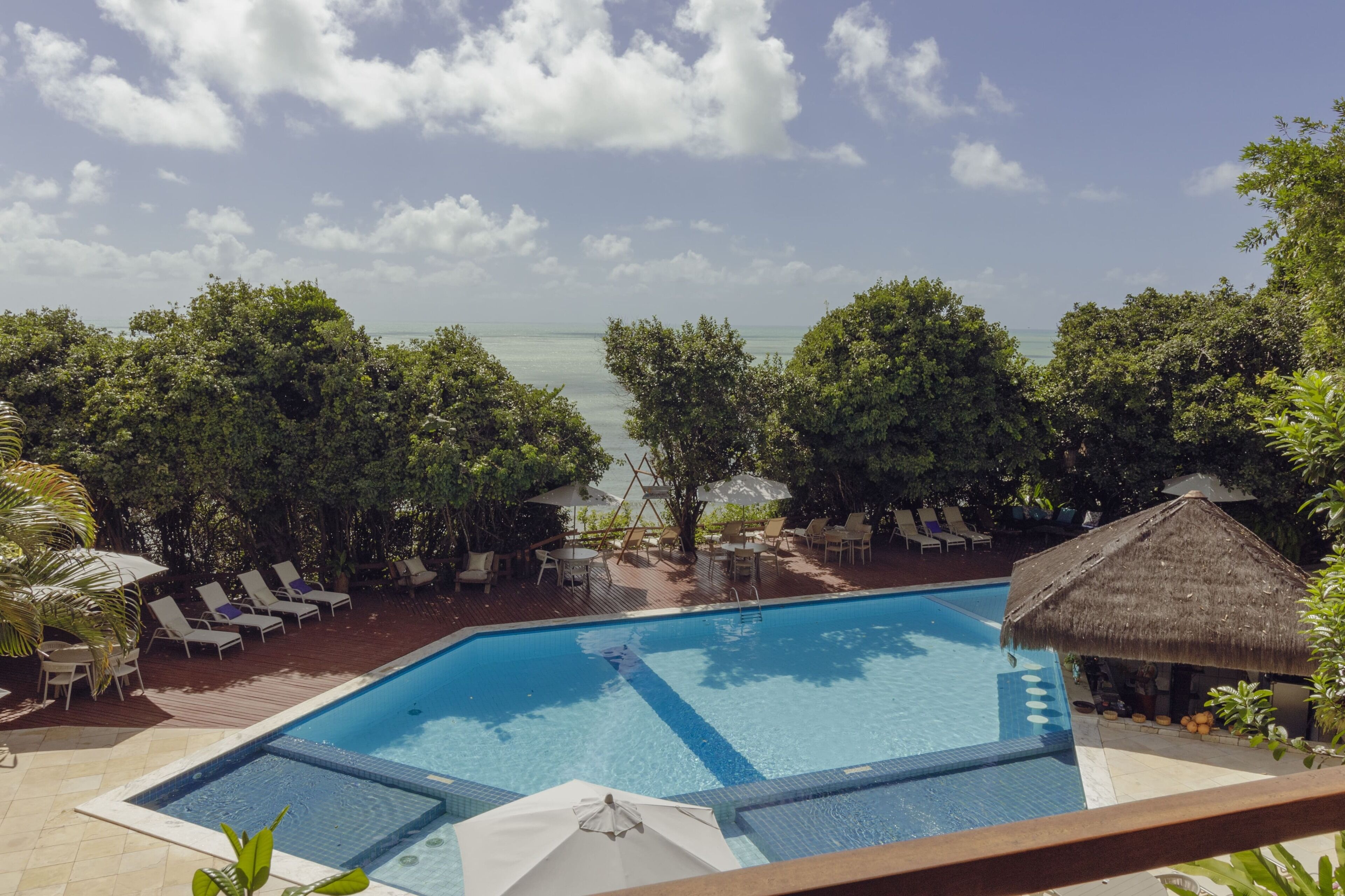 Una piscina al aire libre, sombrillas, sillones reclinables de piscina