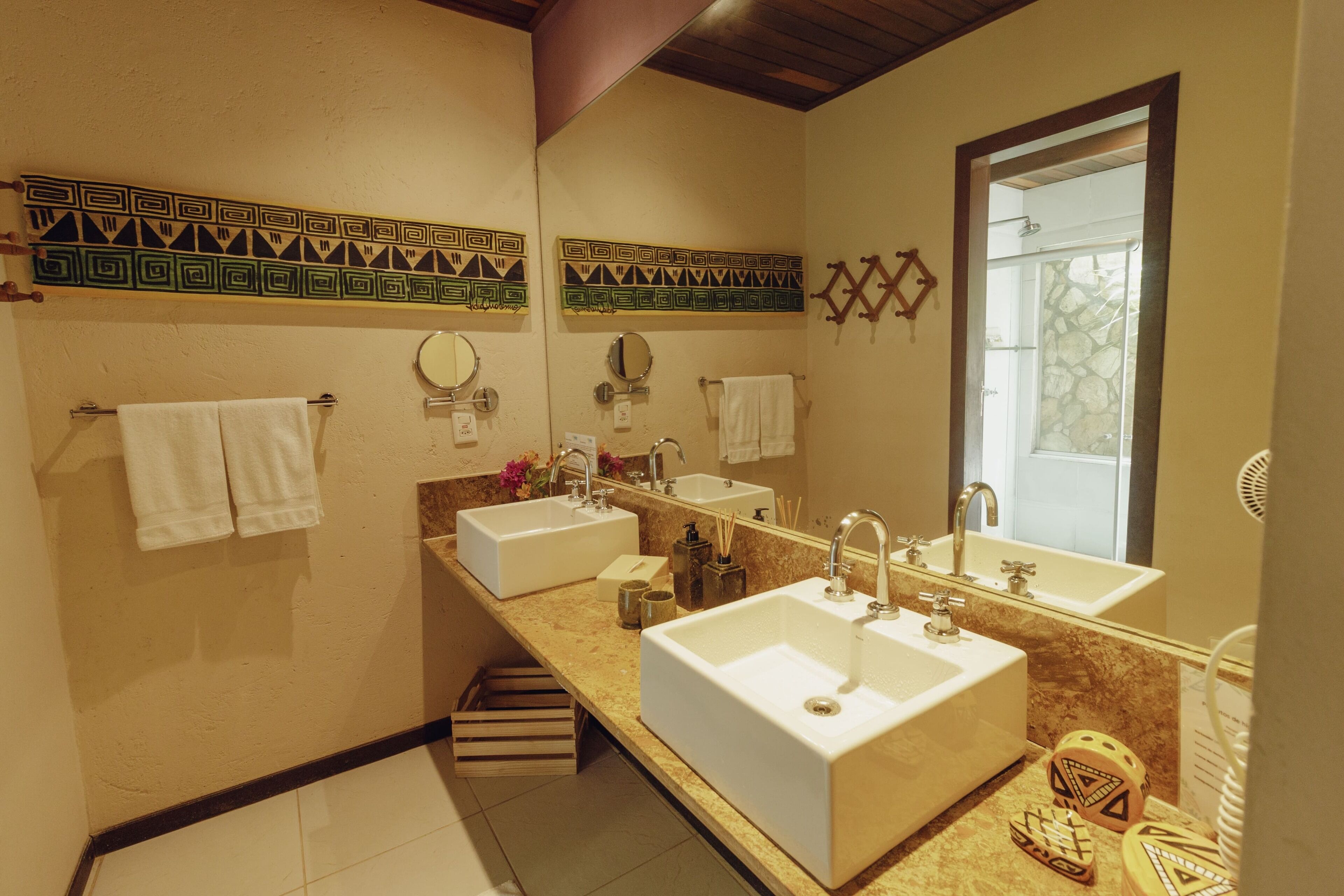 Een badkamer met twee wastafels, een spiegel en decoratieve tegels.
