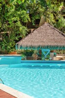 Una piscina al aire libre, sombrillas, sillones reclinables de piscina