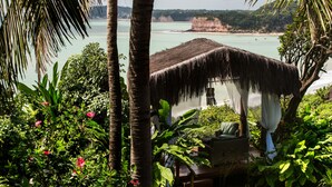A thatched-roof hut with a view of a calm sea and a lush garden. - Ponta do Madeiro (Tibau do Sul)