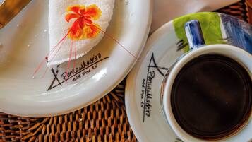 Um prato branco com decoração floral e texto, uma xícara de café e um descanso de palha.
