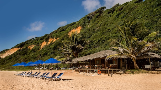 A beach with sun loungers and umbrellas, a thatched-roof hut, and a lifebuoy on the sand. - Ponta do Madeiro (Tibau do Sul)