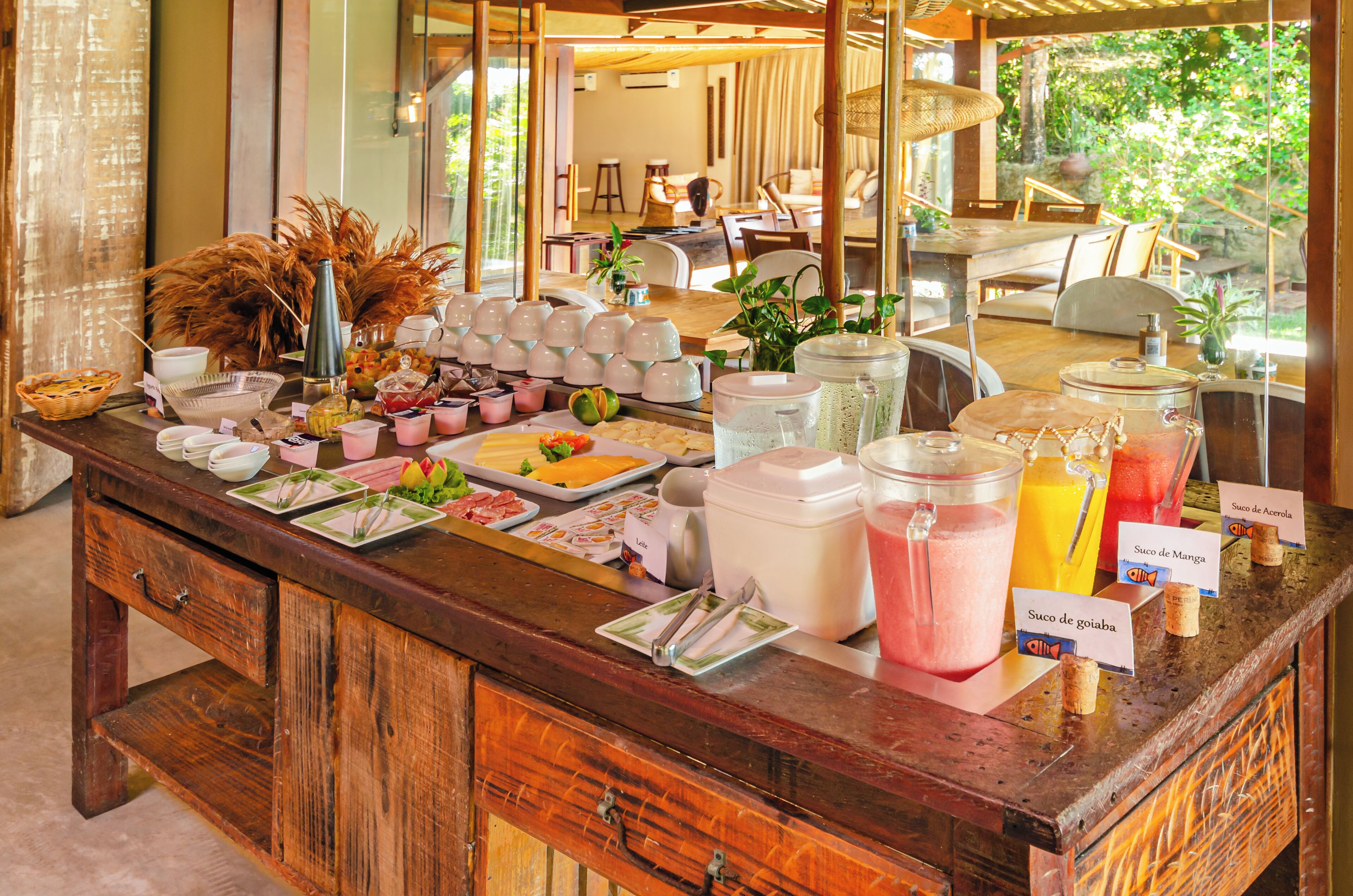 A buffet setup with various food items and beverages, including a fruit platter, sandwiches, and labeled drink options.