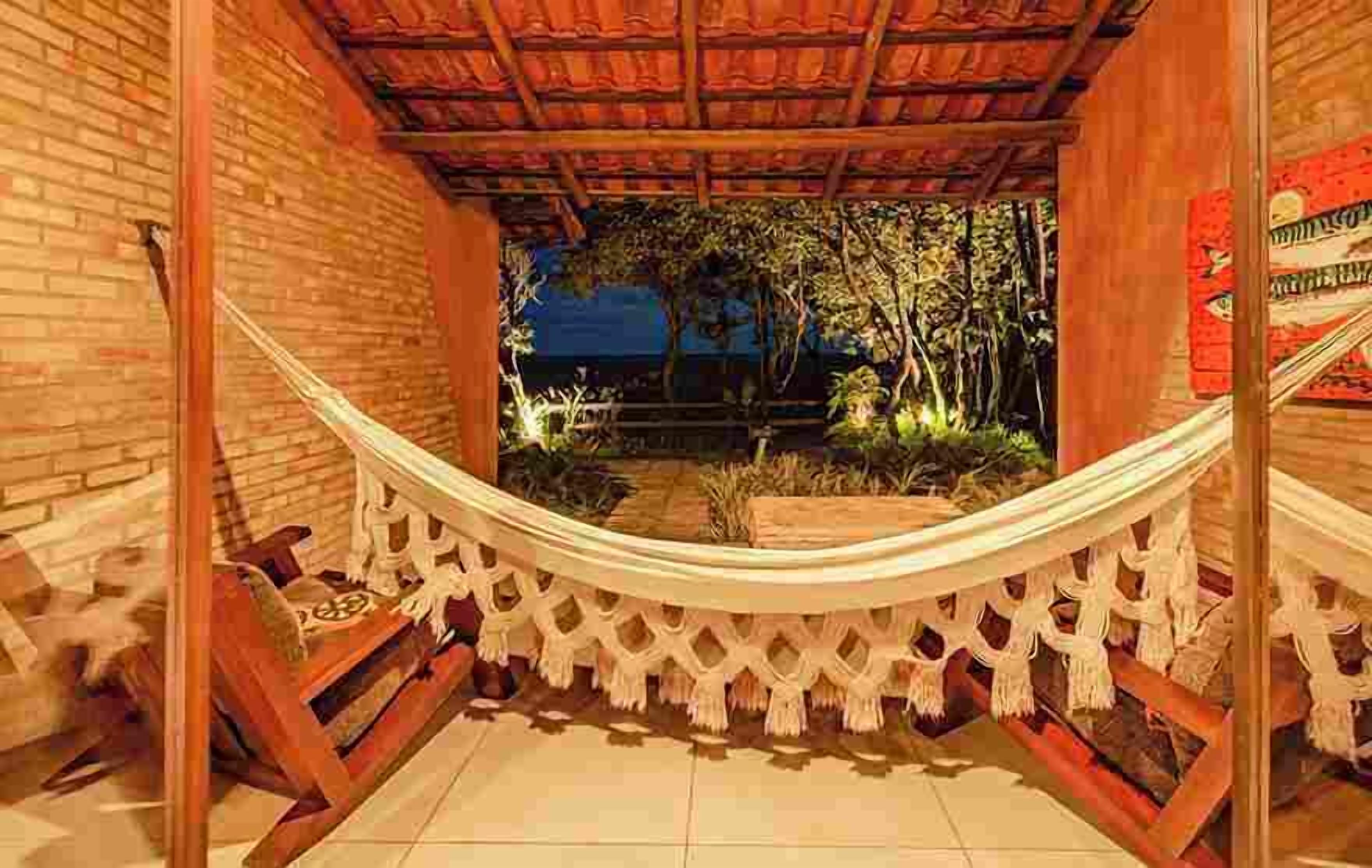 Eine Hängematte unter einer Holzpergola mit Blick auf einen Garten bei Nacht.