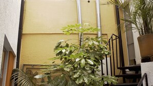 A staircase with a potted plant in the foreground, a metal railing, and a yellow wall in the background. - Apartamentos Los Alcázares (Bogotá)