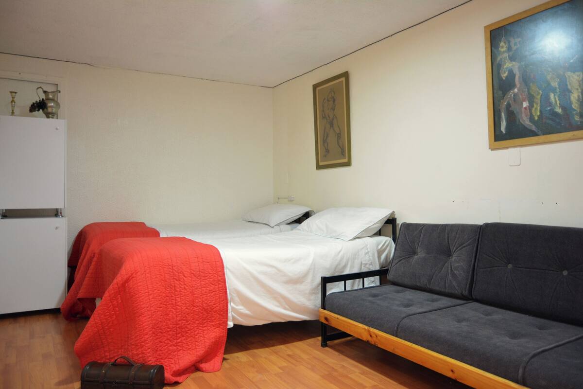 A room with two single beds, a sofa, a small table, and a white wardrobe.