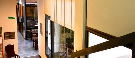 A modern interior with a staircase, a dining area, and a view of the outdoors.