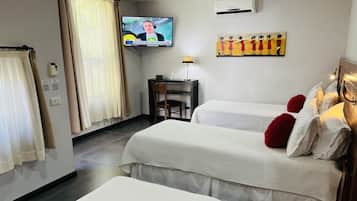 A hotel room with two beds, a television, a desk, and a painting on the wall.