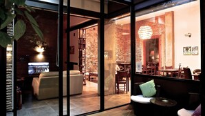 Un intérieur moderne avec une cloison en verre, un canapé, un coin repas et un mur en briques.