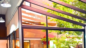 A restaurant with a large glass window, wooden tables, and chairs.