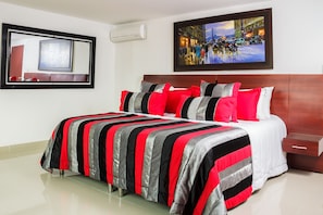 A hotel room with a large bed, a wooden headboard, a framed painting, and a side table. - Hotel Andino (Bucaramanga)