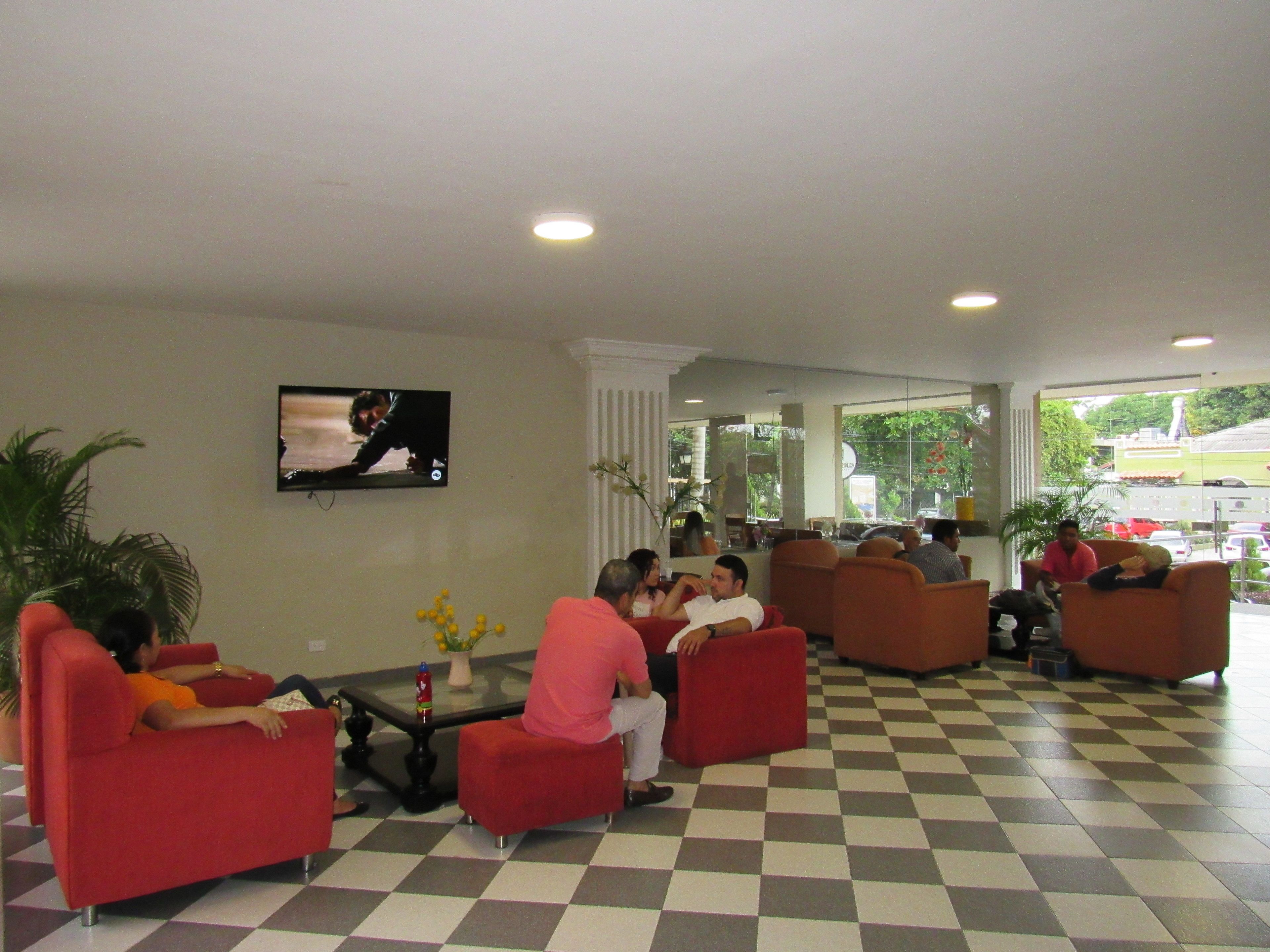 A lobby with red seating, a television, and a checkered floor.