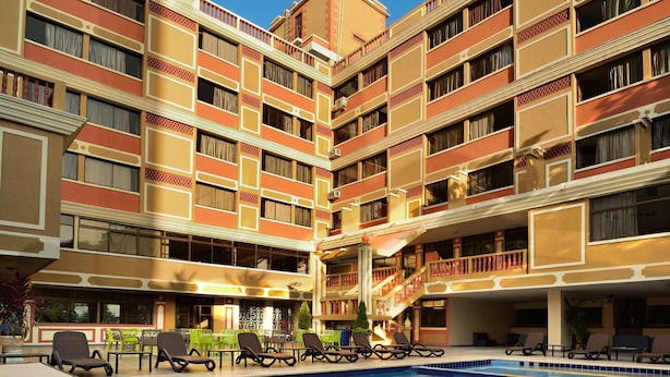 Hotel amb piscina central, múltiples balcons i zones d'estar a l'exterior.