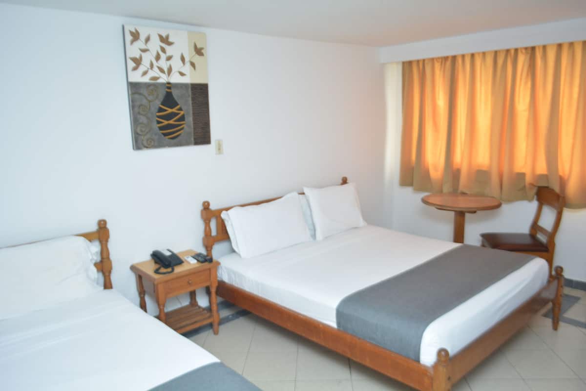 Una habitación de hotel con una cama de madera, una mesita de noche con un teléfono y una pequeña mesa redonda.