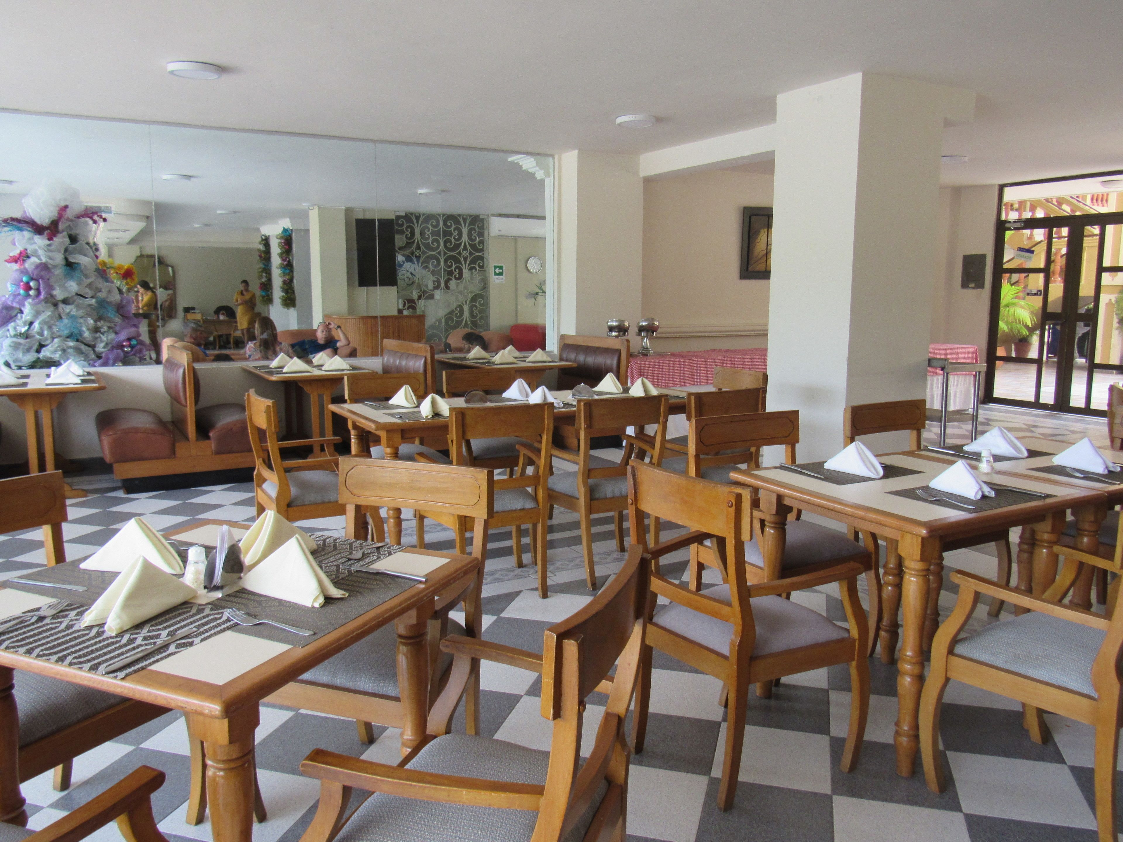 Un restaurante con mesas y sillas de madera, piso de tablones y una decoración navideña.