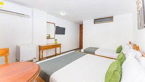 Una habitació d'hotel amb llit, escriptori, cadira, televisió i aire condicionat.