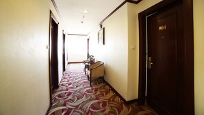 A hallway with patterned carpet, a wooden door with the number 904, and a small table with chairs. - Sunny 3 Hotel Hanoi (Hanoi)