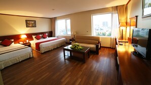 A hotel room with two beds, a sofa, a coffee table, a TV, and large windows with curtains. - Sunny 3 Hotel Hanoi (Hanoi)