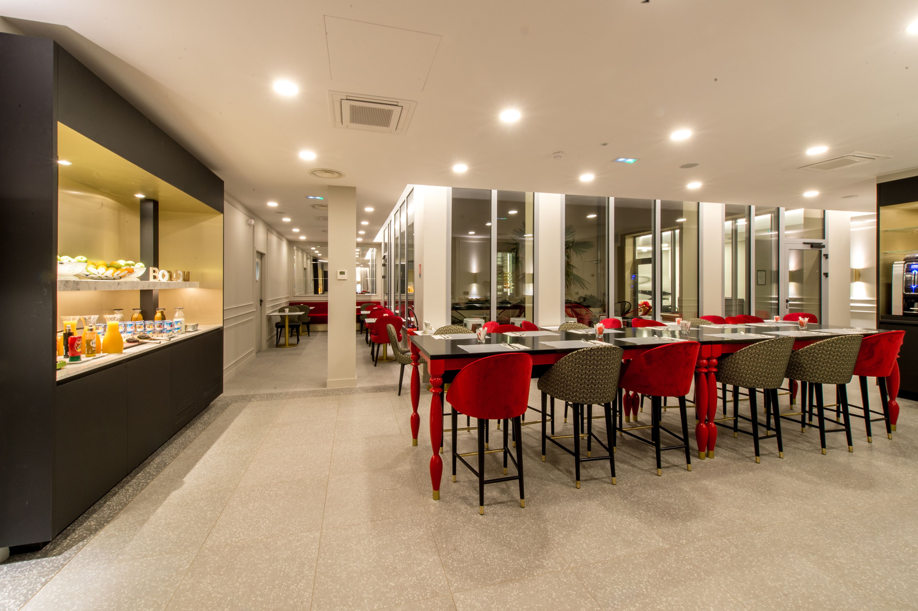 Ein modernes Restaurant mit einer langen Theke, roten Stühlen und einer Auswahl an Speisen.