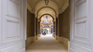 A corridor with white doors, a brick wall, and a view of a building with a balcony. - Ibis Styles Toulouse Capitole (Toulouse)