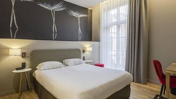Una habitación de hotel moderna con una cama grande, dos mesitas de noche, una silla roja, un escritorio y un ventanal con cortinas.