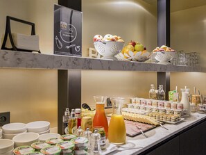A buffet setup with various food items, condiments, and beverages.