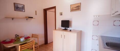 Ein Essbereich mit einem Tisch für zwei Personen, einem Schrank und einer Küchenzeile mit Spüle.
