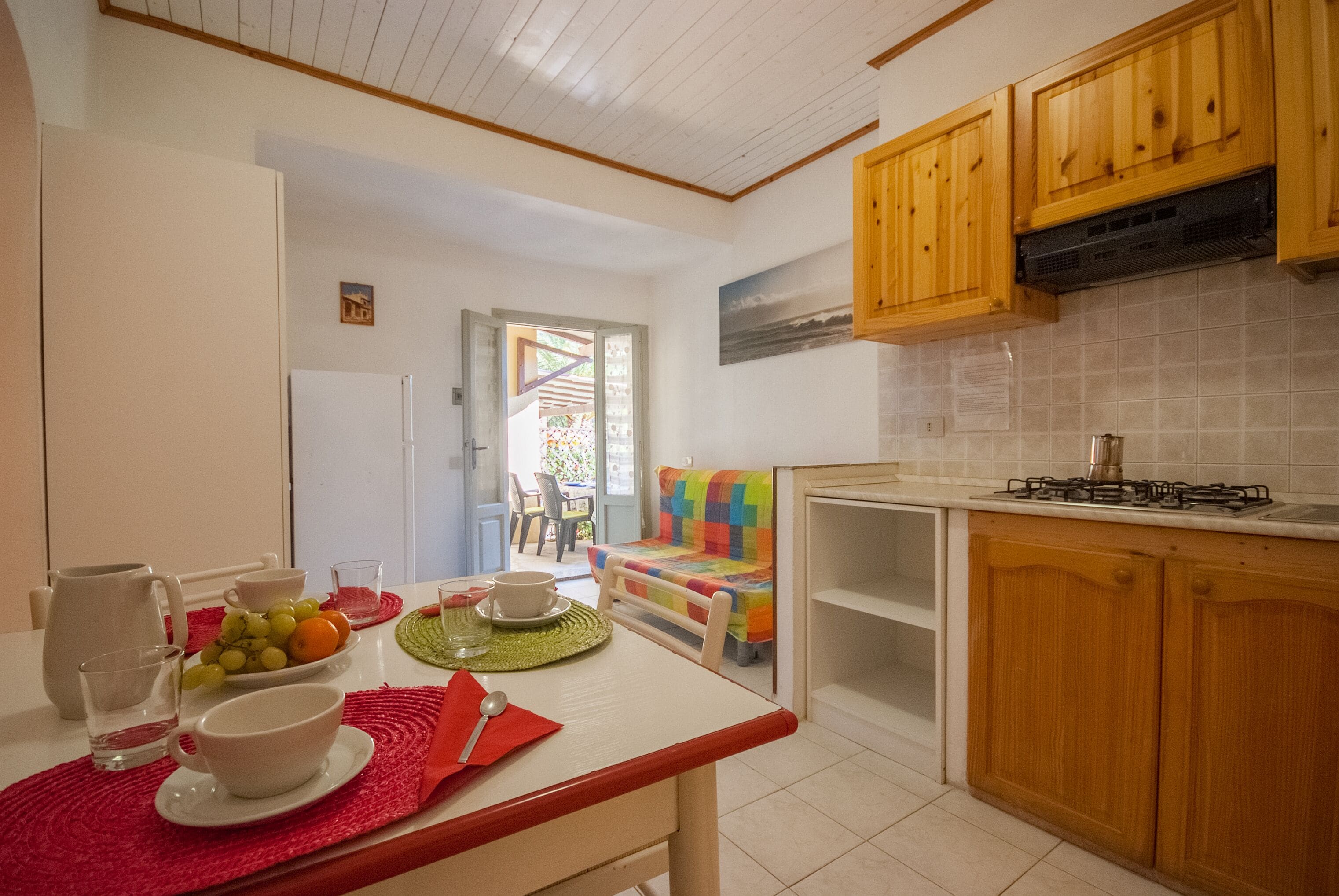 A kitchen with wooden cabinets, a gas stove, and a dining area with a table set for two.