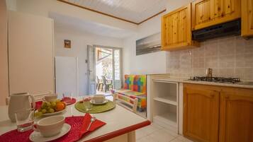 A kitchen with wooden cabinets, a gas stove, and a dining area with a table set for two.