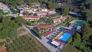 Vista aérea de una zona residencial con varias casas, una piscina y una cancha de tenis.