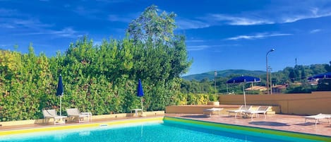 Una piscina al aire libre de temporada, sombrillas, tumbonas