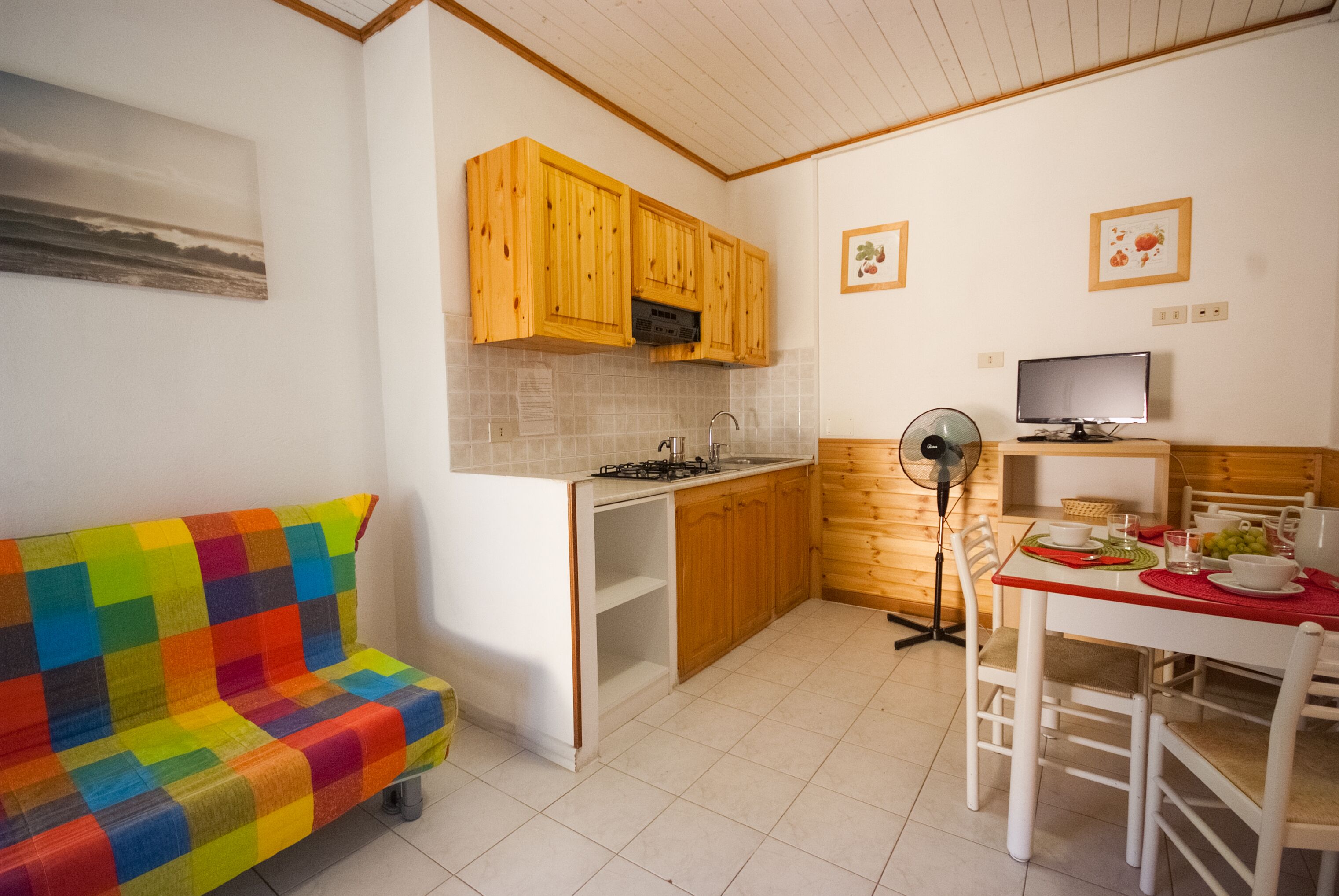 Una cucina compatta con mobili in legno, un fornello a gas e un'area pranzo con tavolo e sedie.