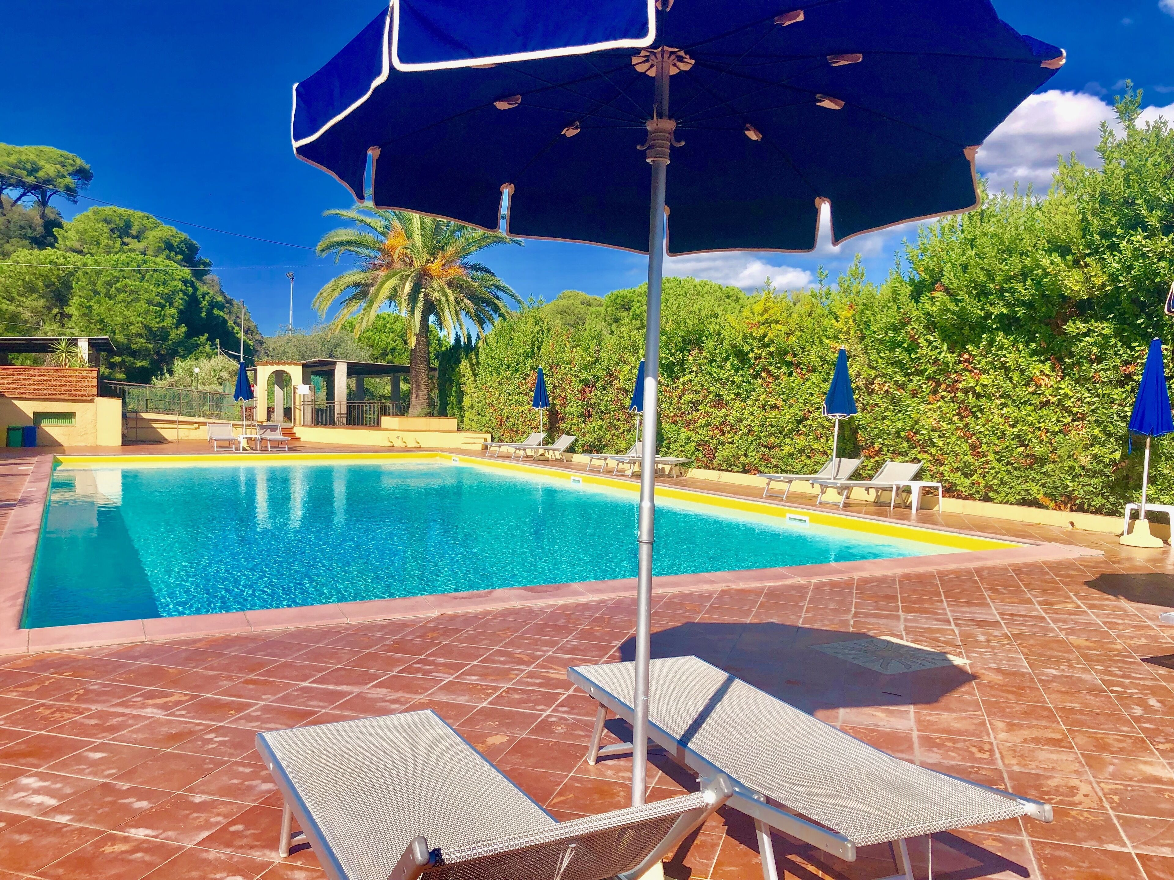 En swimmingpool med kakelbeklädd botten, solstolar och parasoller.