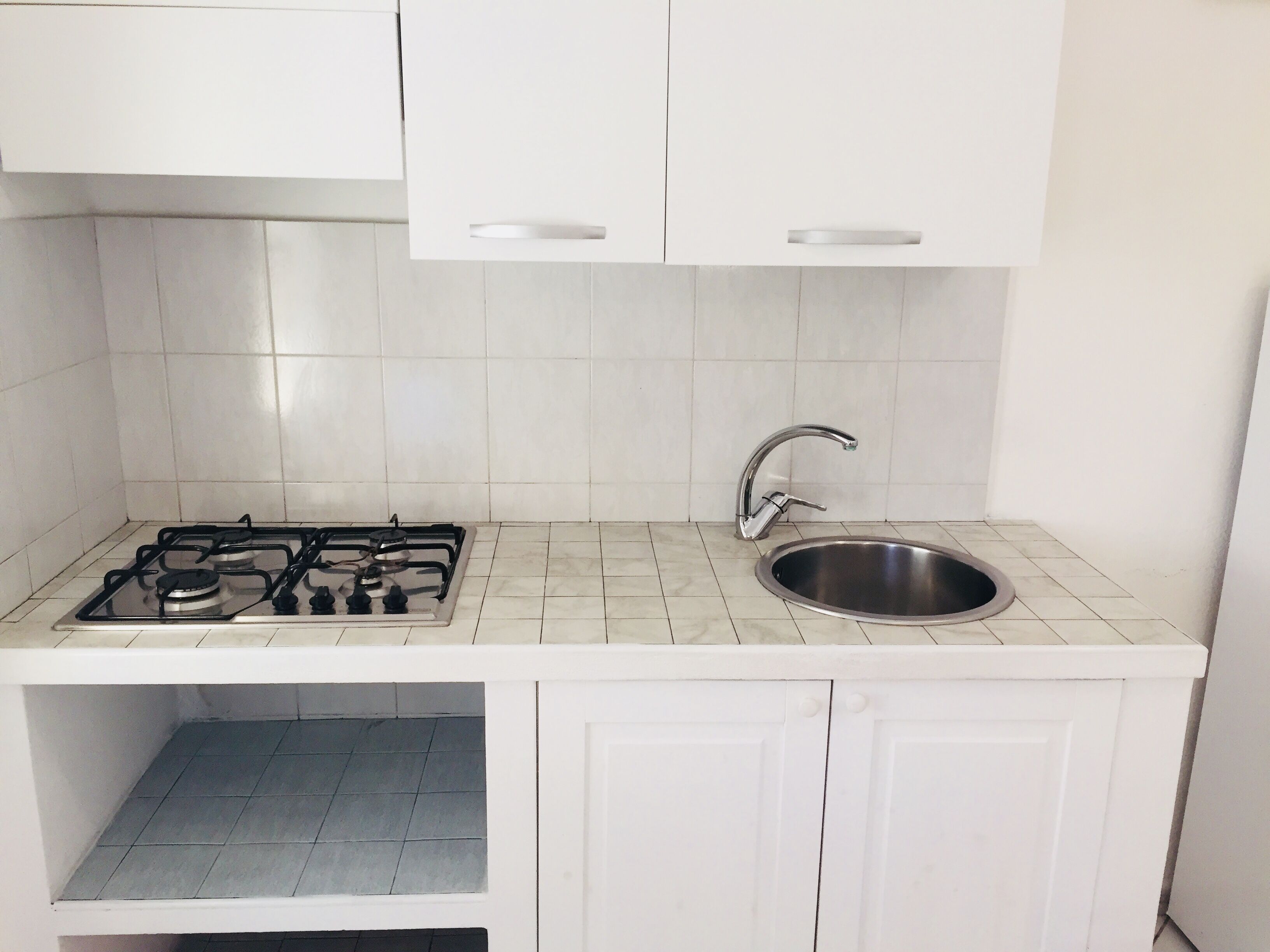 A kitchen with white cabinets, a stainless steel sink, and a gas stove.