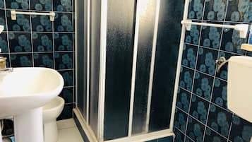 Une salle de bain avec douche, toilettes et lavabo.