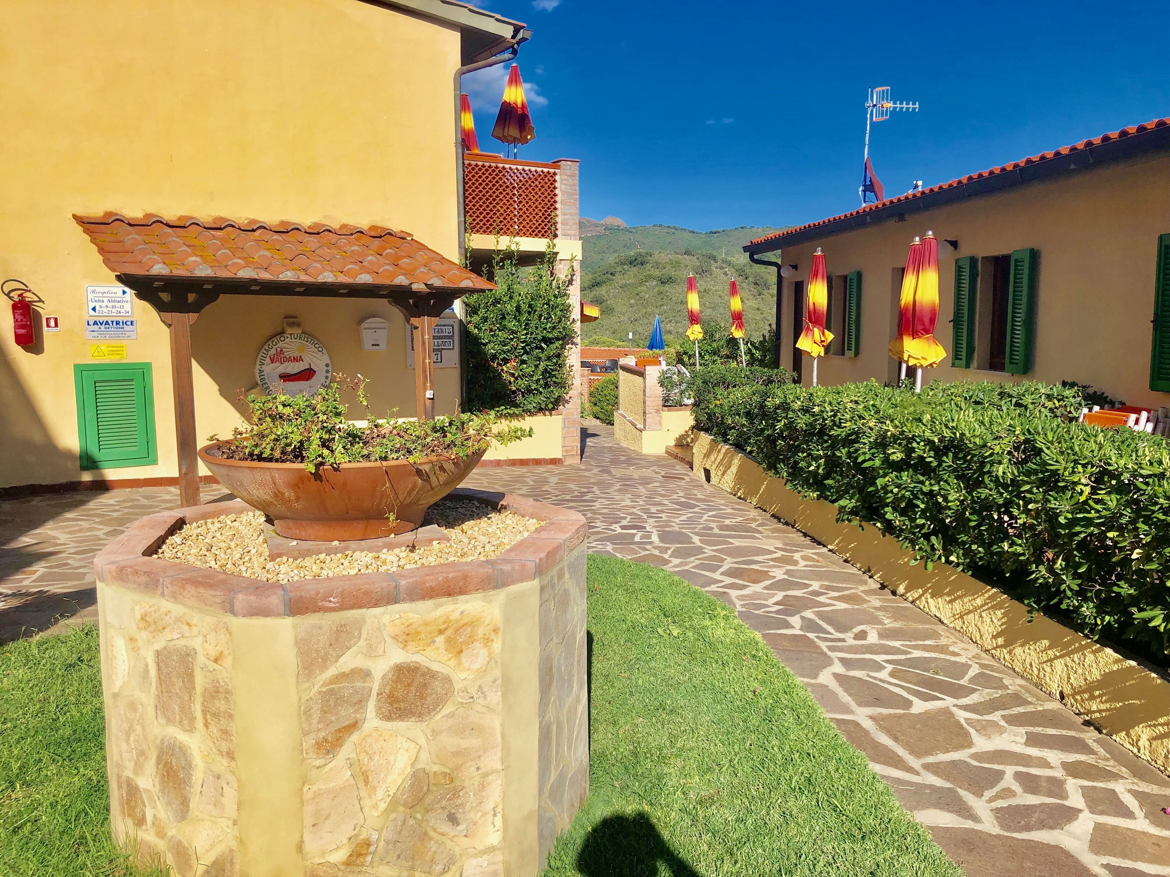Un patio con una jardinera de piedra, techo de tejas y un camino empedrado.