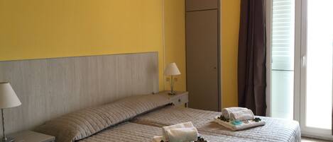 A hotel room with a bed, a nightstand, a lamp, and a window with curtains.
