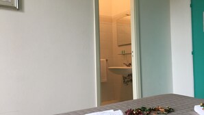 A room with a bed, a bathroom visible through an open door, and a green wall. - Hotel Castelsardo Domus Beach (Castelsardo)