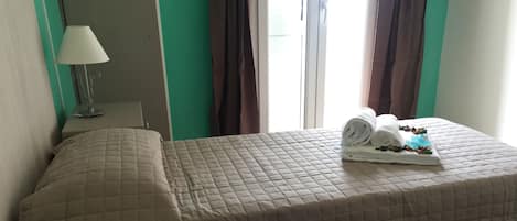 Habitación de hotel con dos camas, una lámpara y una ventana con cortinas.