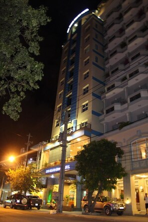 A multi-story building with illuminated signage, a visible entrance, and parked cars.