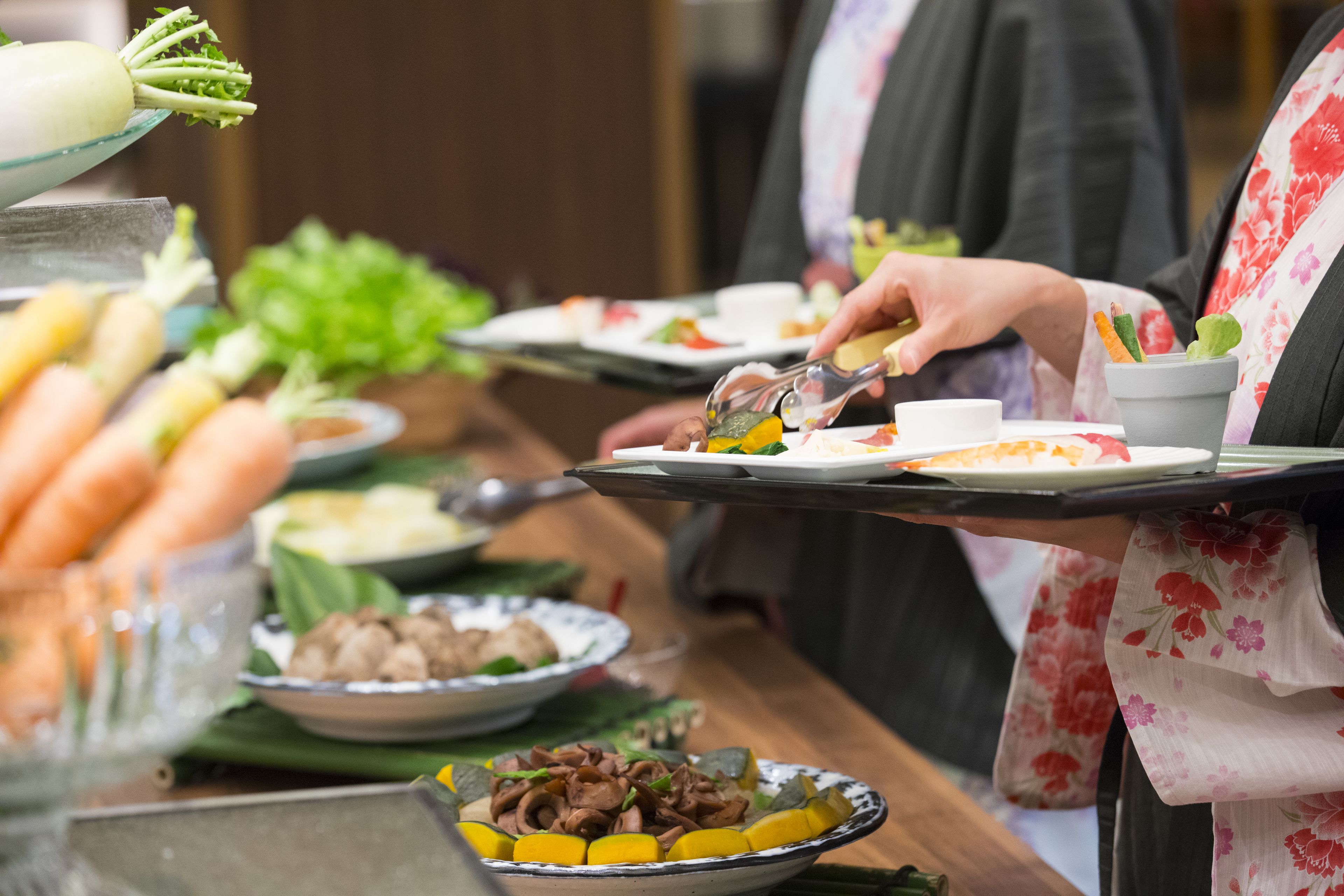 Una mesa de buffet con diversos platos y una persona sirviendo comida.