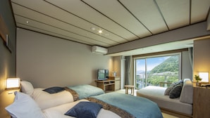 Habitación de hotel con dos camas, televisión, una mesita y ventana con vista a la montaña.