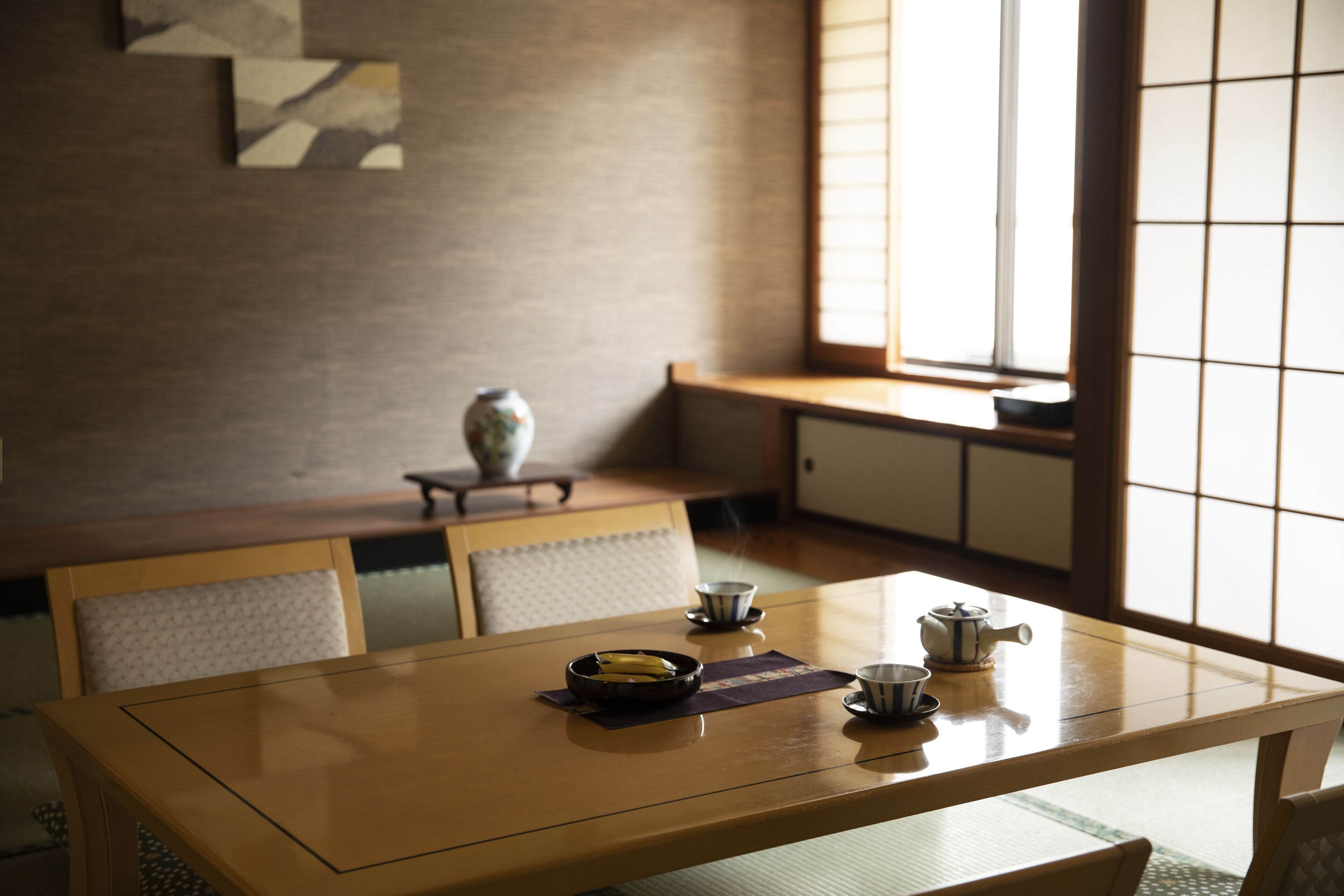 Una habitación tradicional japonesa con suelo de tatami, una mesa baja y un juego de té, y puertas correderas.