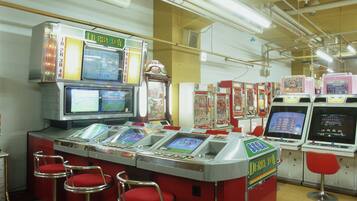Una hilera de máquinas de arcade con un letrero que dice 'DERBY DAY' y una fila de taburetes rojos delante.