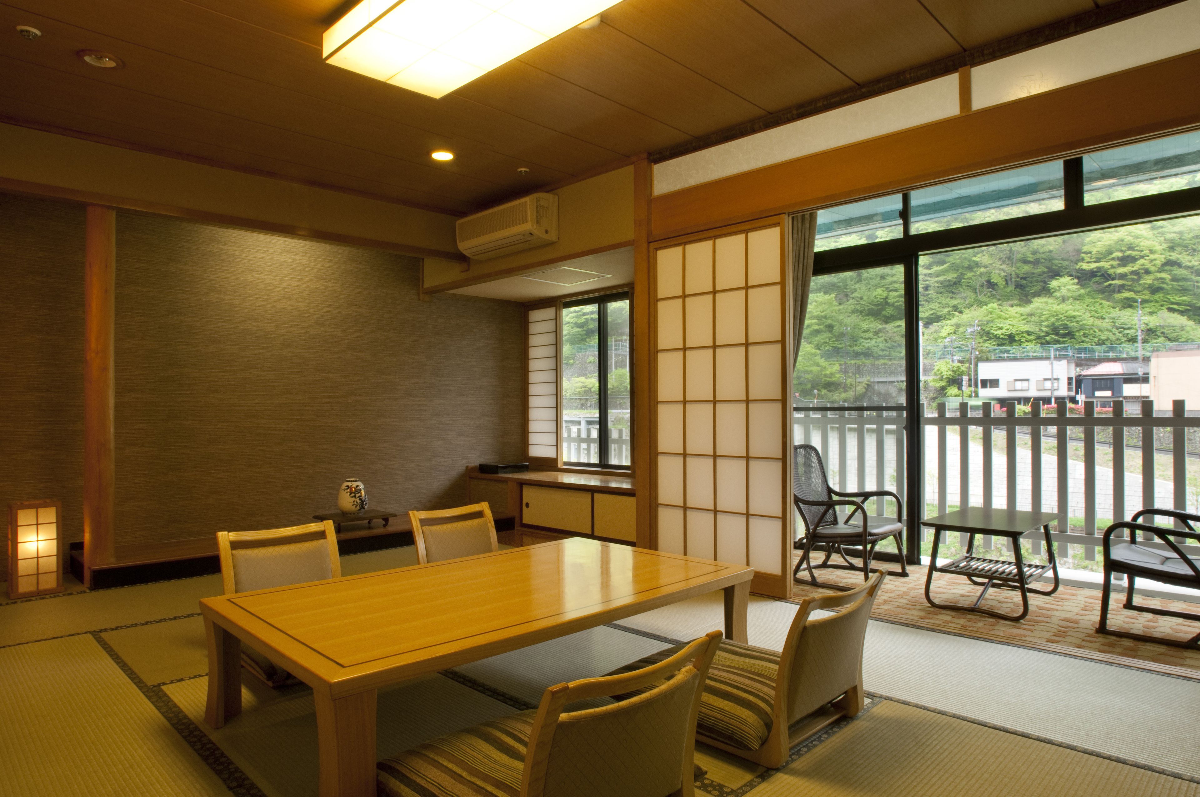 A traditional Japanese room with tatami flooring, a wooden table, and chairs.