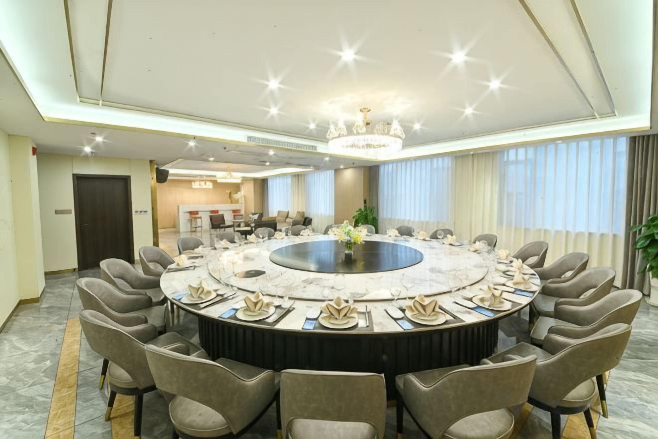 Un salón de conferencias con una mesa redonda, sillas y una araña.